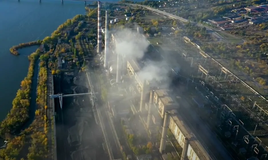 Aerial view of a power plant, its emissions visible against the backdrop of the surrounding landscape
