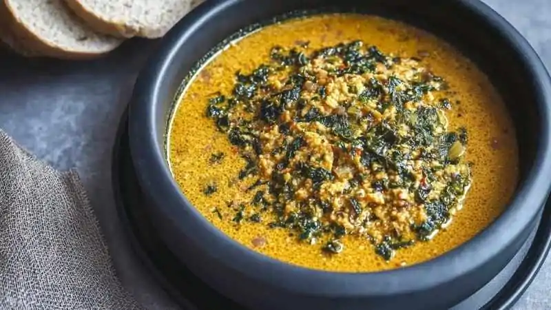 Bowl of Nigerian Egusi soup with leafy greens and ground melon seeds