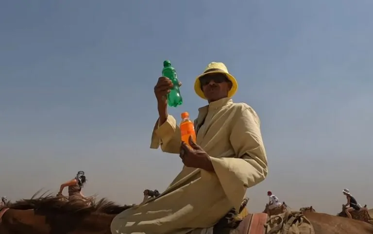 A man on a camel, offering drinks in the Egyptian desert