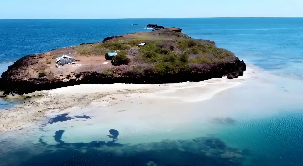 Pristine white sand beach hugs the volcanic rock of a secluded Lamu Archipelago island