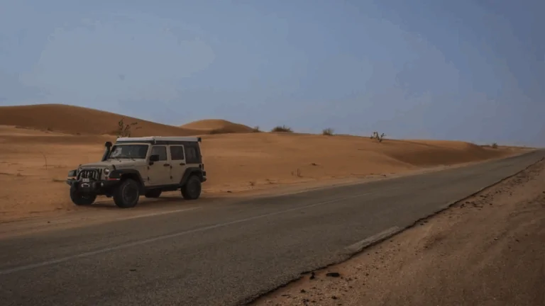 A white 4x4 parked by a desert road, showing a drive across Africa