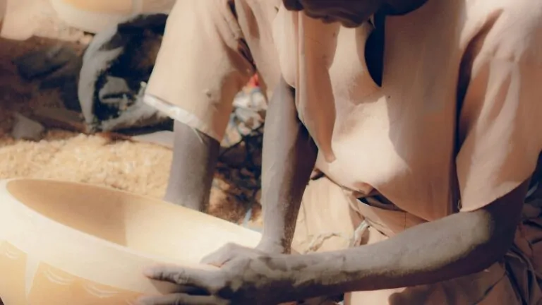 A person carefully holds a carved calabash bowl, showing its role in sharing a calabash traditions across West Africa