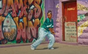 A young woman dances in front of vibrant graffiti-covered walls