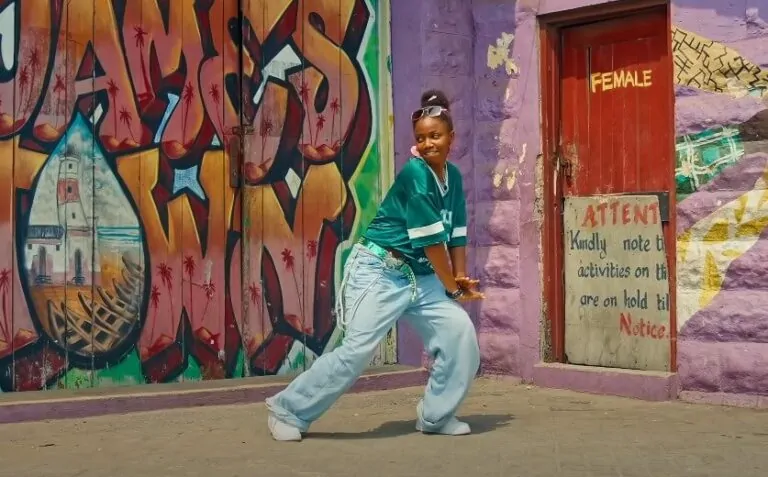 A young woman dances in front of vibrant graffiti-covered walls