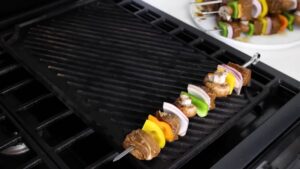 Metal skewers with marinated meat and vegetables are placed on a preheated grill pan to start cooking