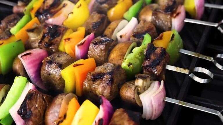 Grilled Shish Kabobs with beef, bell peppers, onions, and mushrooms cooking on metal skewers over open flame