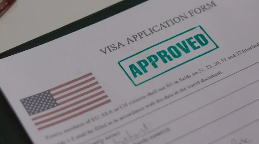 A visa application form displayed on a table, with visible text fields and instructions for completion