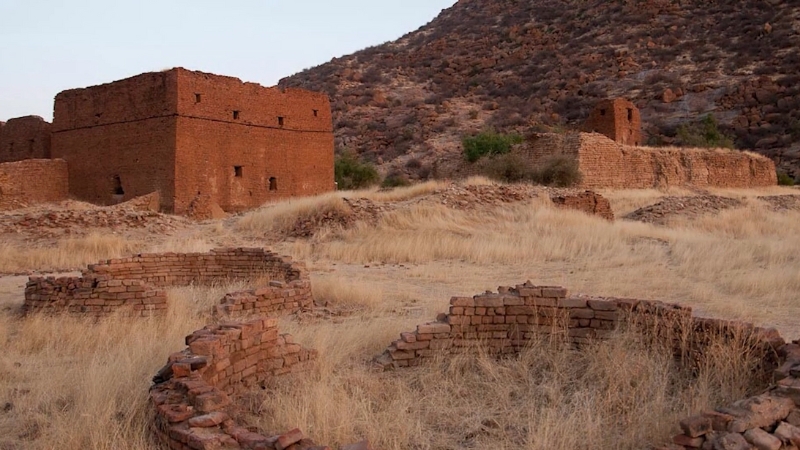 Ruins of old brick structures from the Wadai Sultanate set against a dry hillside in the Sahel