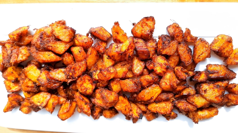A tray of baked or air-fried kelewele showing evenly browned, crispy plantain pieces