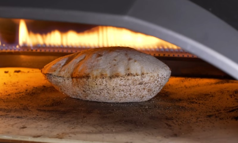 A Baladi loaf baking in a traditional wood-fired oven