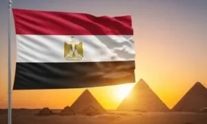 Egyptian flag waving in front of the pyramids under a clear blue sky