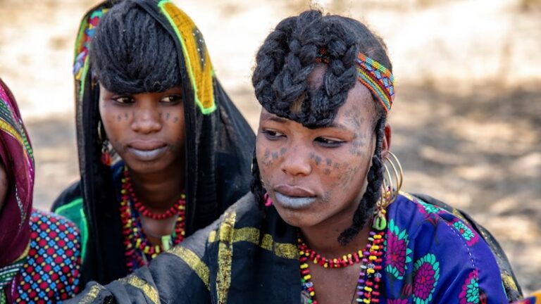 Fulani people in traditional attire with braided hairstyles and facial tattoos