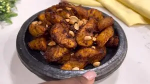 A bowl of golden-brown Kelewele served with roasted peanuts