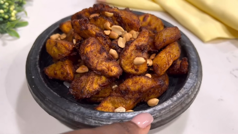 A bowl of golden-brown Kelewele served with roasted peanuts