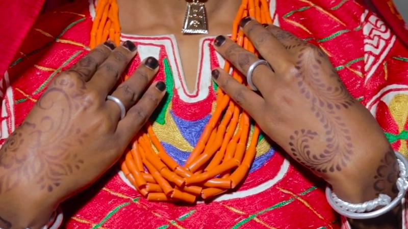 Kanuri woman with coral beads, silver jewelry, and henna-decorated hands