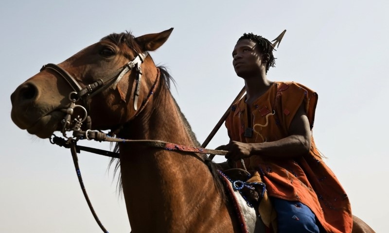 A man in traditional attire rides a horse, showcasing cultural heritage