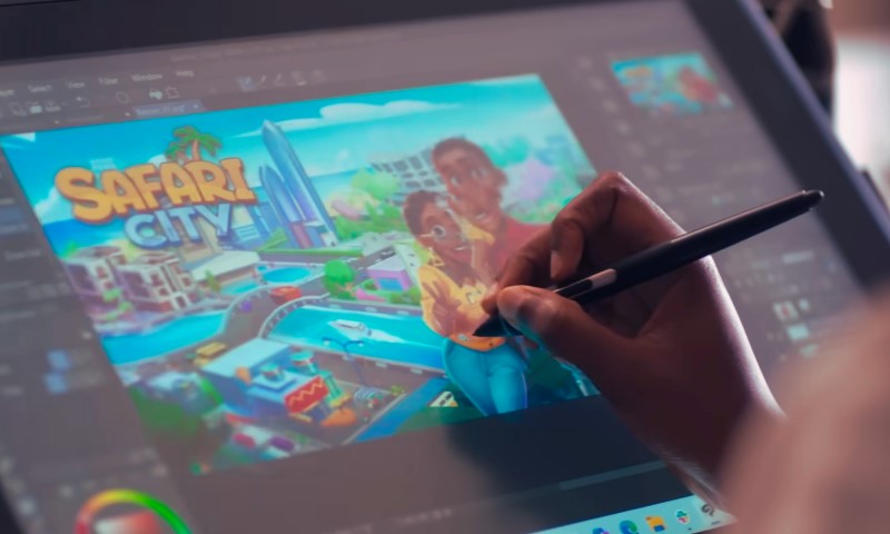 A person is using a stylus to draw on a digital tablet connected to a computer screen