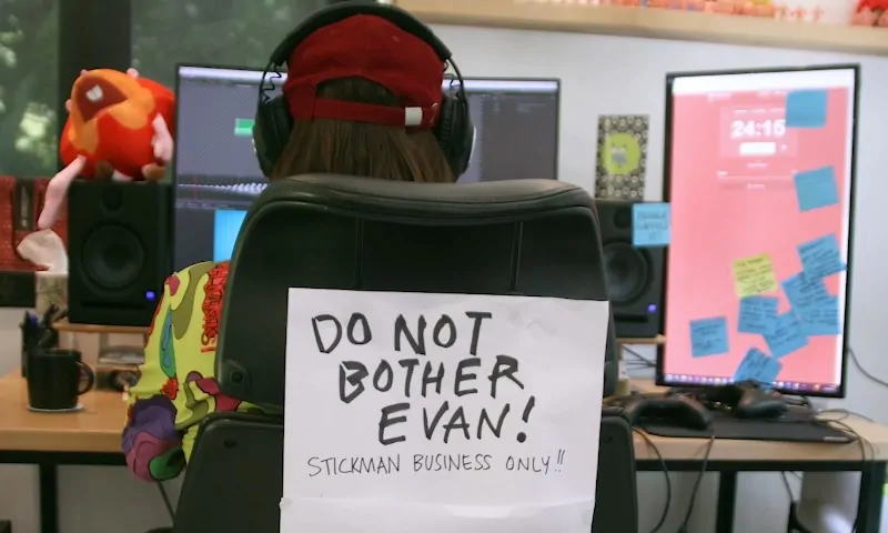 A person sitting at a desk with a sign reading "Don't do not bother Evan."