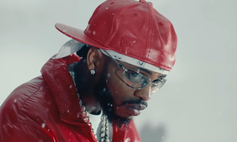 Diamond Platnumz in a red cap and jacket, with clear glasses and diamond earrings