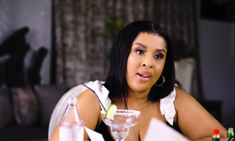 Nonku Williams sits at a table with a cocktail glass garnish with a lime slice