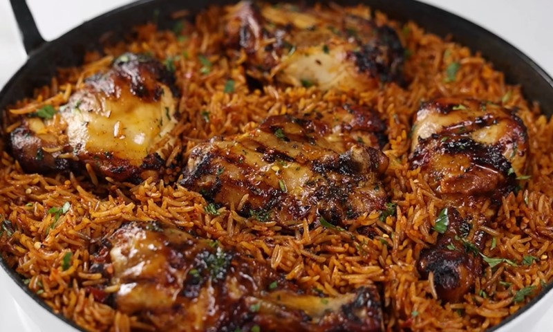 Jollof with grilled chicken thighs in a pan