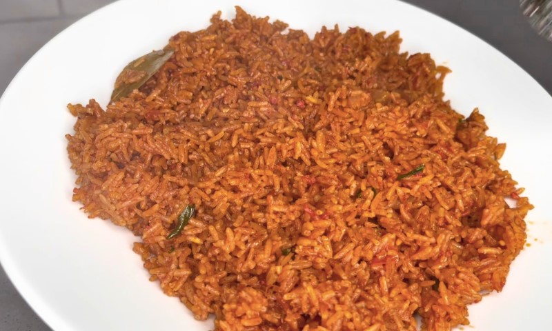 A white plate filled with spicy, red-orange jollof rice