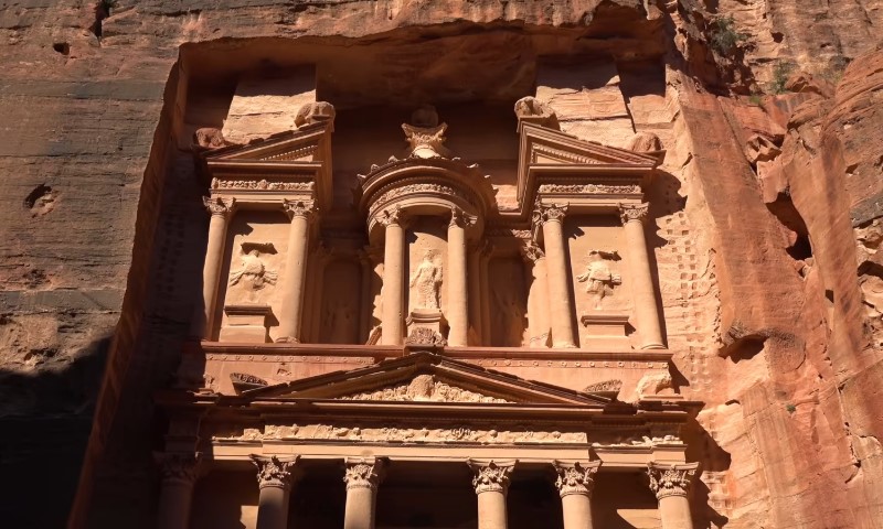 Ancient rock-carved facade of Petra's Treasury, bathed in warm sunlight