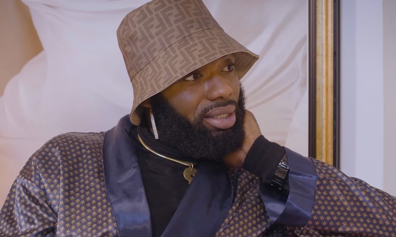 Swanky Jerry wearing a patterned bucket hat, matching robe, and gold necklace