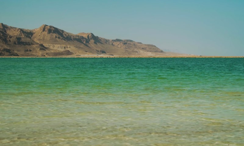 Clear turquoise waters of the Dead Sea under a blue sky