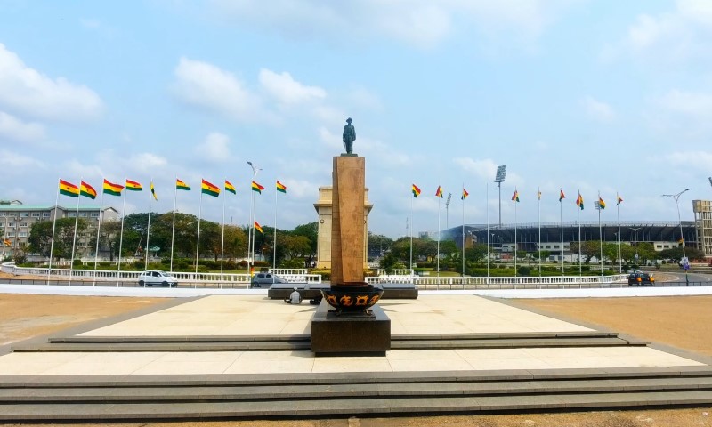 Statue on a pedestal in an open plaza, with surrounding rows of Ghana flags