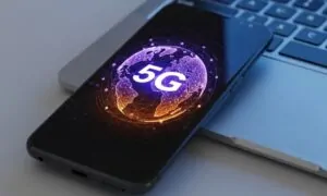 Smartphone displaying a glowing purple globe with "5G" text, resting on a laptop